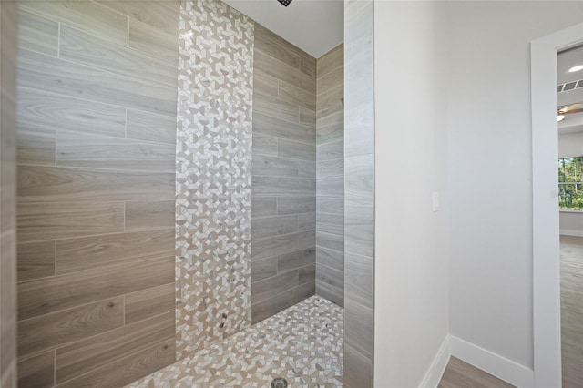 bathroom featuring a tile shower and wood-type flooring