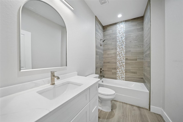 full bathroom with vanity, tiled shower / bath combo, and toilet