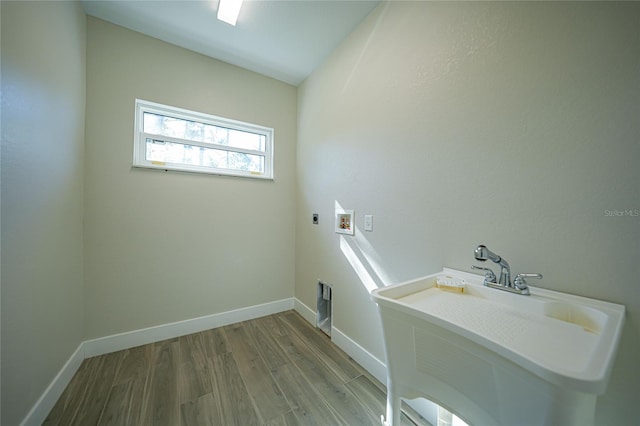 clothes washing area with hookup for an electric dryer, washer hookup, light wood-type flooring, and sink