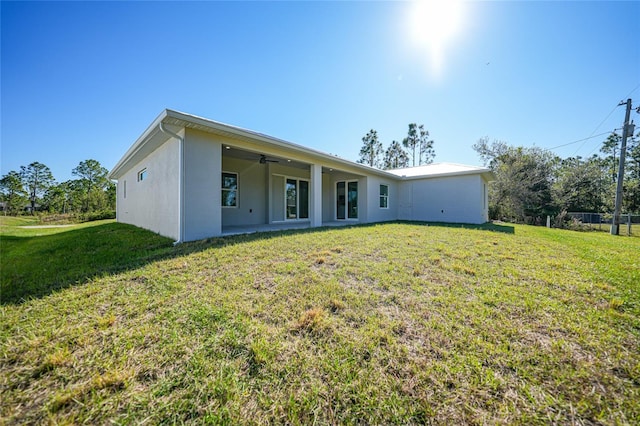 rear view of property featuring a yard, a patio, and ceiling fan