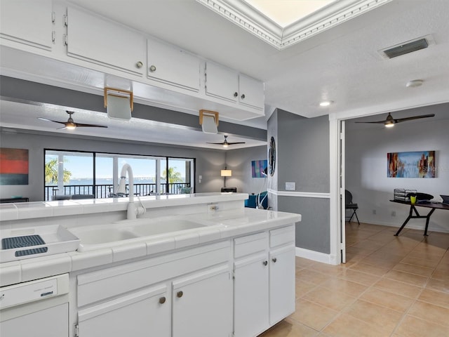 kitchen with sink, white cabinets, tile countertops, white dishwasher, and light tile patterned floors