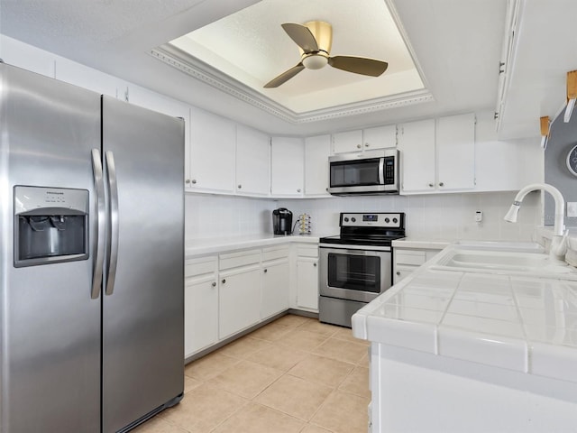 kitchen with a raised ceiling, white cabinetry, and appliances with stainless steel finishes