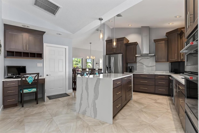 kitchen featuring stainless steel refrigerator with ice dispenser, wall chimney exhaust hood, decorative light fixtures, a kitchen island, and lofted ceiling