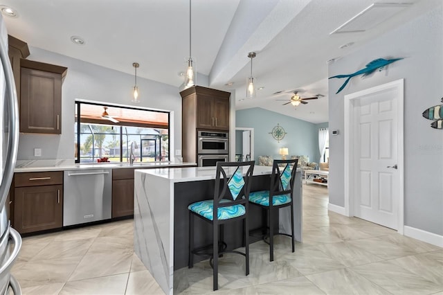 kitchen with stainless steel appliances, vaulted ceiling, ceiling fan, sink, and a center island