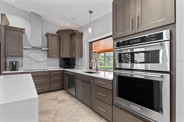 kitchen with pendant lighting, sink, wall chimney exhaust hood, appliances with stainless steel finishes, and tasteful backsplash