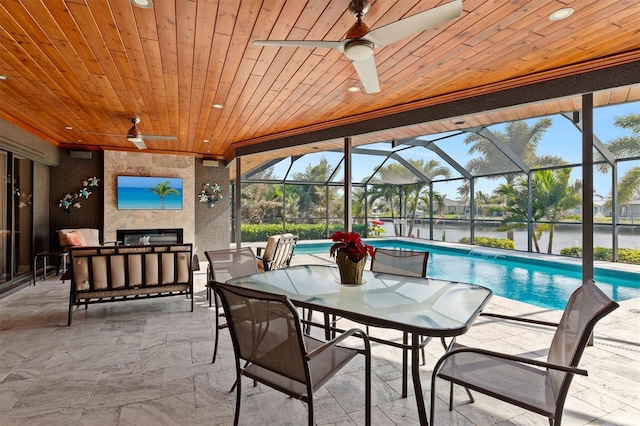 exterior space featuring a lanai, ceiling fan, a water view, a fireplace, and a patio