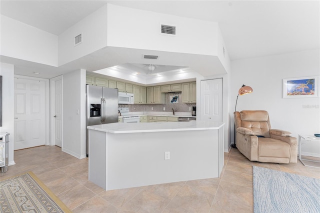 kitchen with green cabinets, stainless steel appliances, backsplash, a raised ceiling, and light tile patterned floors