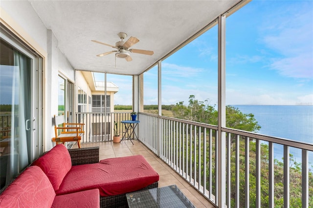 sunroom featuring ceiling fan and a water view