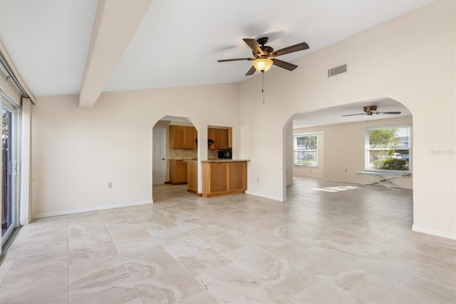 unfurnished living room with ceiling fan and lofted ceiling with beams