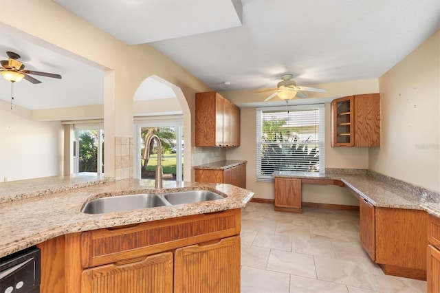 kitchen with dishwasher, sink, ceiling fan, decorative backsplash, and light stone countertops