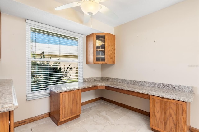 unfurnished office featuring built in desk and ceiling fan