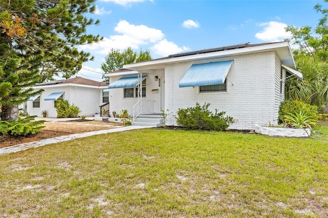 view of front of property with a front lawn and solar panels