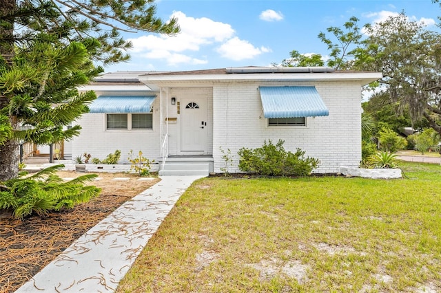 bungalow-style home with a front yard and solar panels