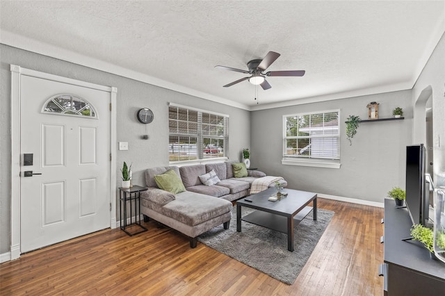 living room featuring wood-type flooring, a textured ceiling, and ceiling fan