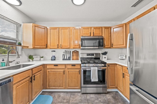 kitchen featuring sink, stainless steel appliances, a textured ceiling, and light tile patterned flooring