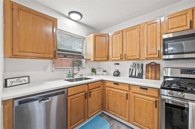 kitchen with appliances with stainless steel finishes, sink, and a textured ceiling