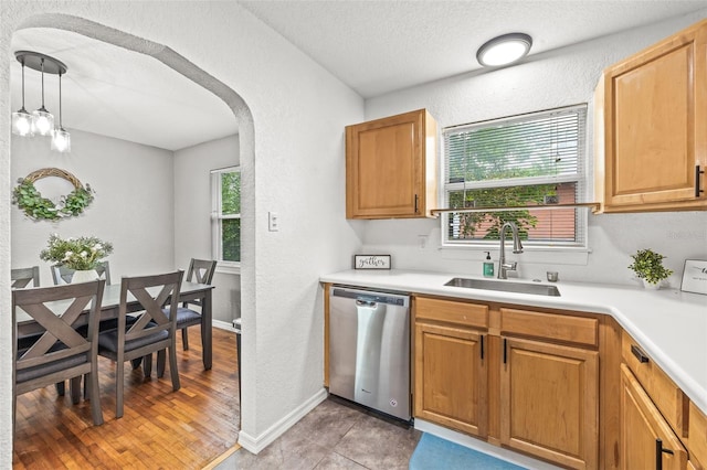 kitchen with dishwasher, sink, hanging light fixtures, and a textured ceiling