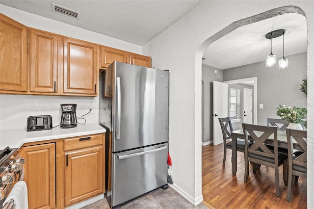 kitchen featuring pendant lighting, hardwood / wood-style flooring, stainless steel appliances, and a textured ceiling