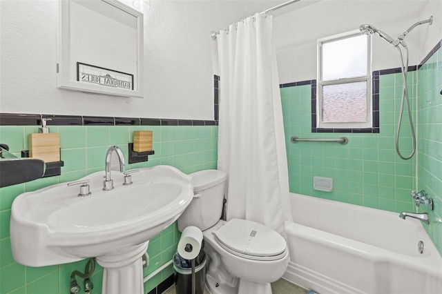 full bathroom with shower / tub combo with curtain, sink, toilet, and tile walls