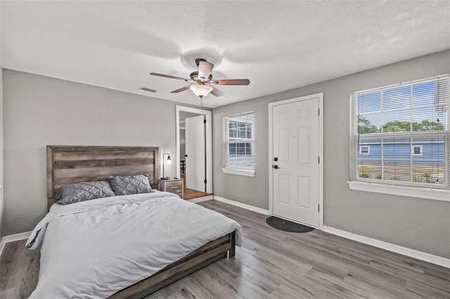 bedroom featuring ceiling fan, wood-type flooring, and a textured ceiling