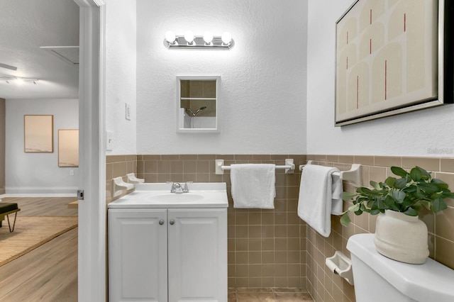 bathroom with tile walls, hardwood / wood-style floors, vanity, and toilet