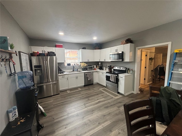 kitchen featuring white cabinetry, sink, hardwood / wood-style floors, and appliances with stainless steel finishes