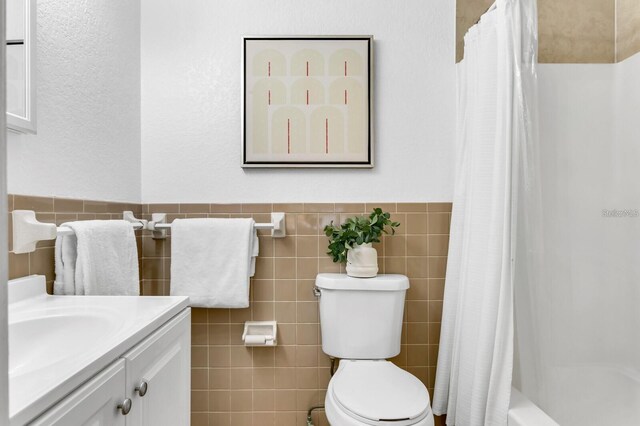 full bathroom featuring shower / tub combo with curtain, vanity, toilet, and tile walls