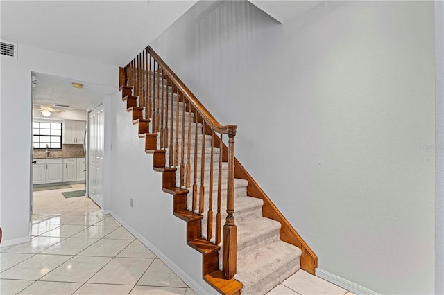 stairway featuring ceiling fan, tile patterned flooring, and sink