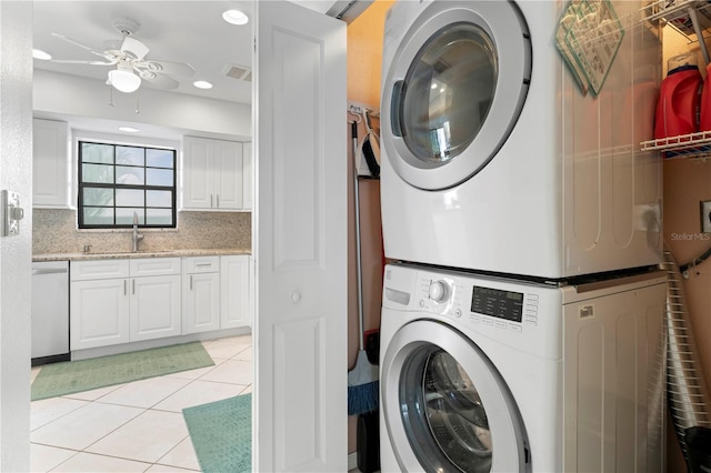 laundry area featuring ceiling fan, sink, light tile patterned floors, and stacked washing maching and dryer