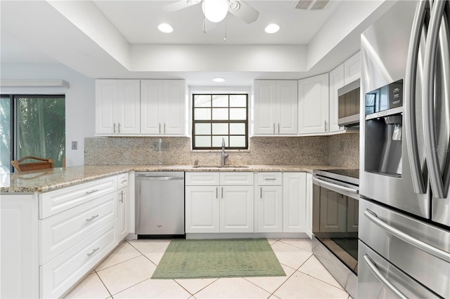 kitchen featuring white cabinets, sink, light tile patterned floors, kitchen peninsula, and stainless steel appliances