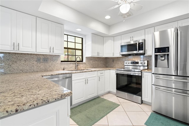 kitchen featuring white cabinetry, sink, tasteful backsplash, light tile patterned floors, and appliances with stainless steel finishes