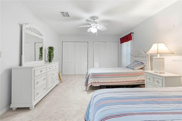 carpeted bedroom featuring ceiling fan and two closets