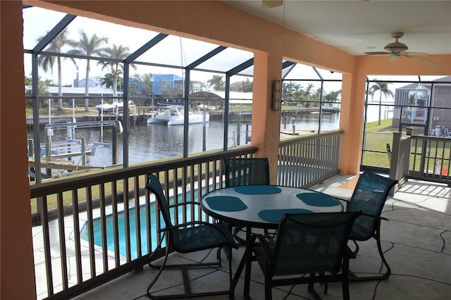 sunroom with ceiling fan and a water view