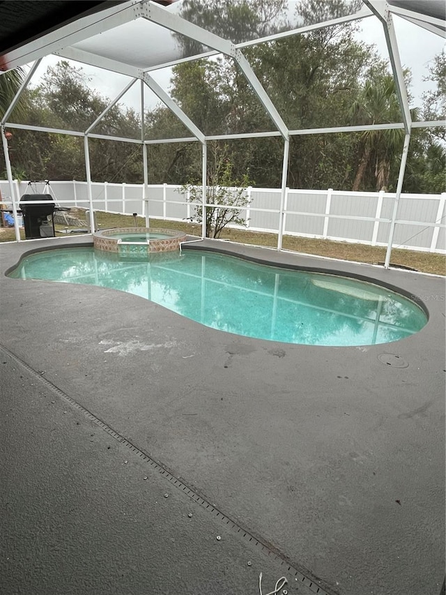 view of pool with glass enclosure, a grill, and an in ground hot tub