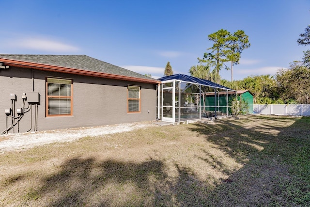 back of house with a lawn and glass enclosure