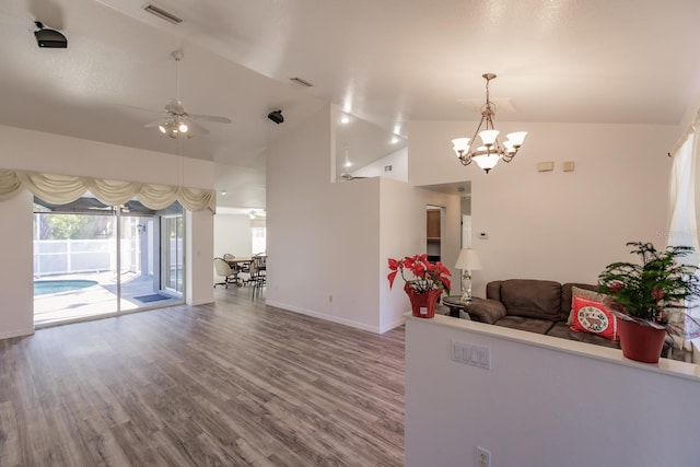 living room featuring ceiling fan with notable chandelier, hardwood / wood-style flooring, and vaulted ceiling