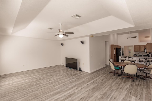 unfurnished living room featuring a tray ceiling, light hardwood / wood-style flooring, and ceiling fan