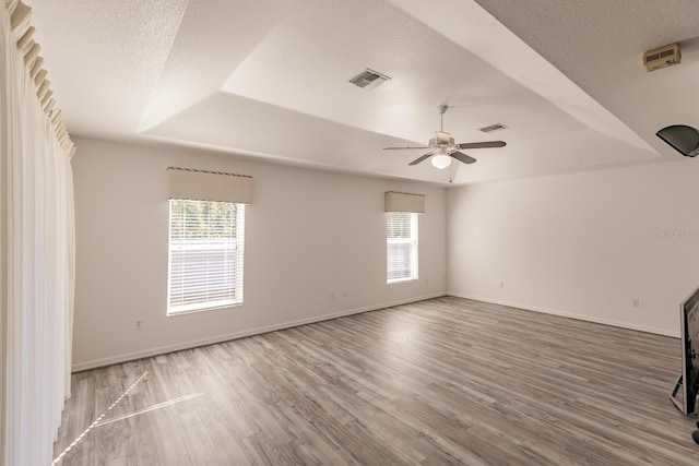 spare room with a tray ceiling, ceiling fan, hardwood / wood-style floors, and a textured ceiling