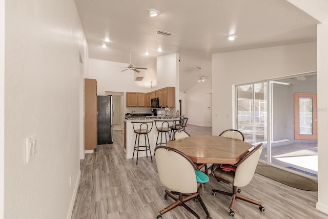 dining room with high vaulted ceiling, light hardwood / wood-style flooring, and ceiling fan