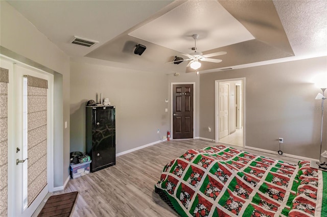 bedroom with a tray ceiling, ceiling fan, and light hardwood / wood-style floors