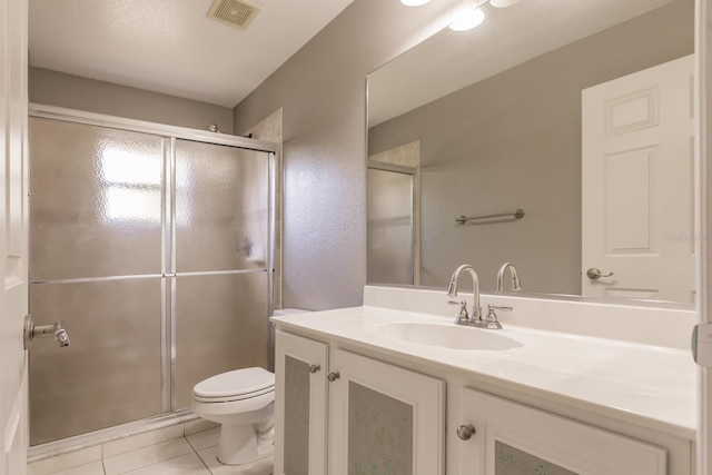 bathroom featuring tile patterned floors, vanity, toilet, and a shower with shower door