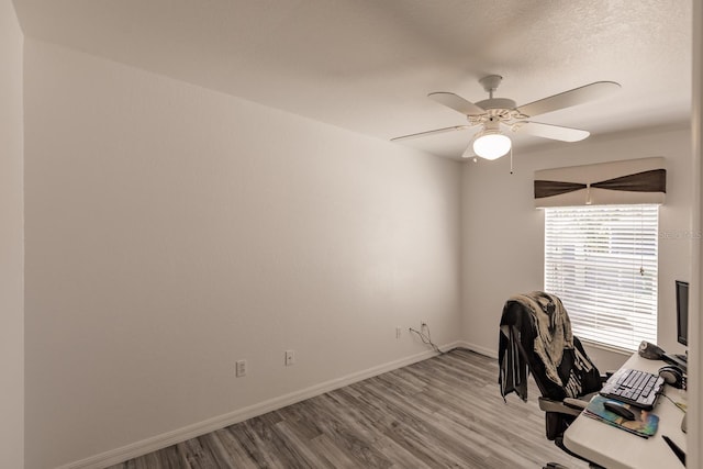 unfurnished office with light wood-type flooring, ceiling fan, and a healthy amount of sunlight