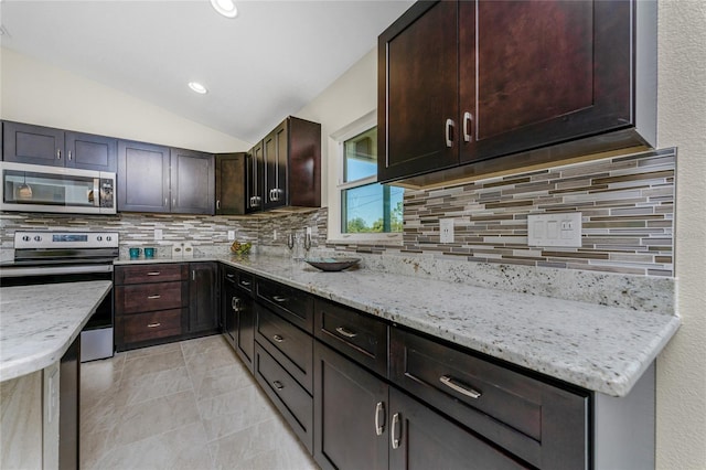 kitchen with decorative backsplash, stainless steel appliances, light stone counters, and lofted ceiling