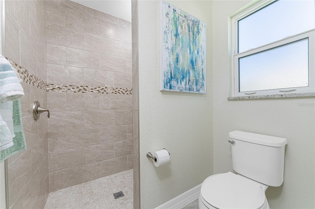 bathroom featuring tiled shower and toilet