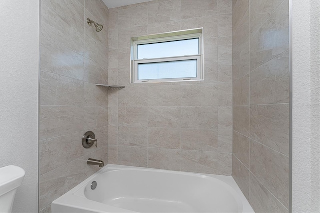 bathroom featuring toilet and tiled shower / bath combo