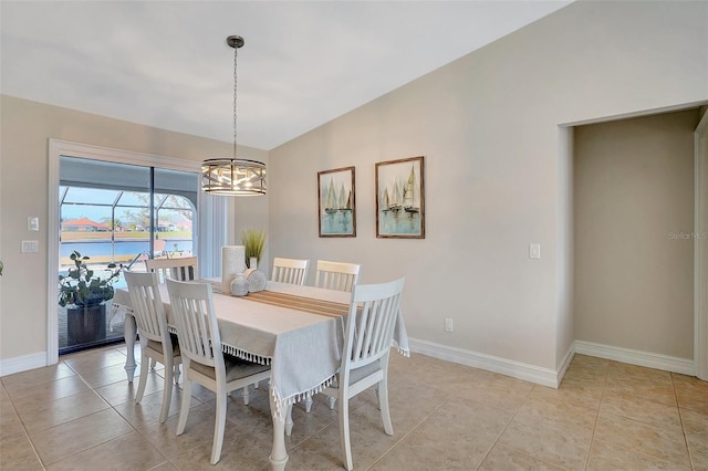 tiled dining area with a chandelier, a water view, and vaulted ceiling