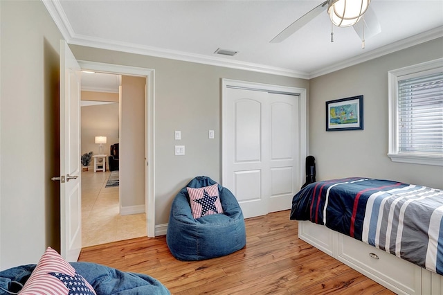 bedroom with ceiling fan, a closet, hardwood / wood-style flooring, and ornamental molding