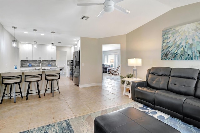 tiled living room with ceiling fan, sink, and vaulted ceiling