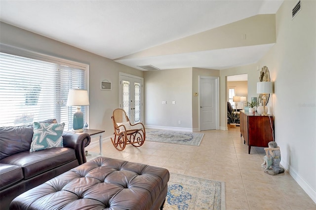 living room featuring vaulted ceiling, light tile patterned floors, and french doors