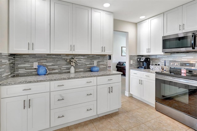 kitchen featuring light tile patterned flooring, appliances with stainless steel finishes, and white cabinets